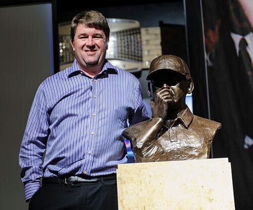 Chris Moneymaker posing next to a bronze bust of himself at an unveiling