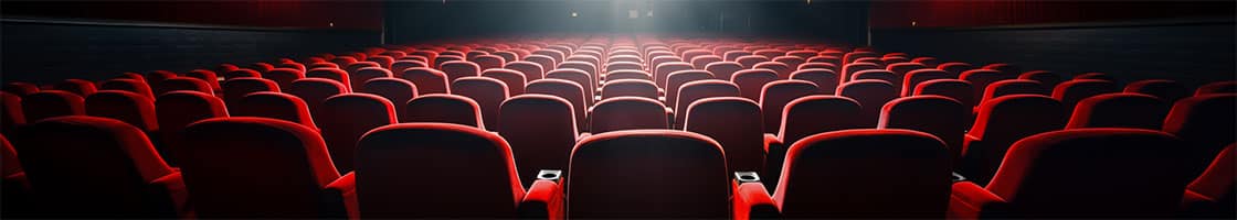 rows of seats in an empty theatre under the glow of a screen